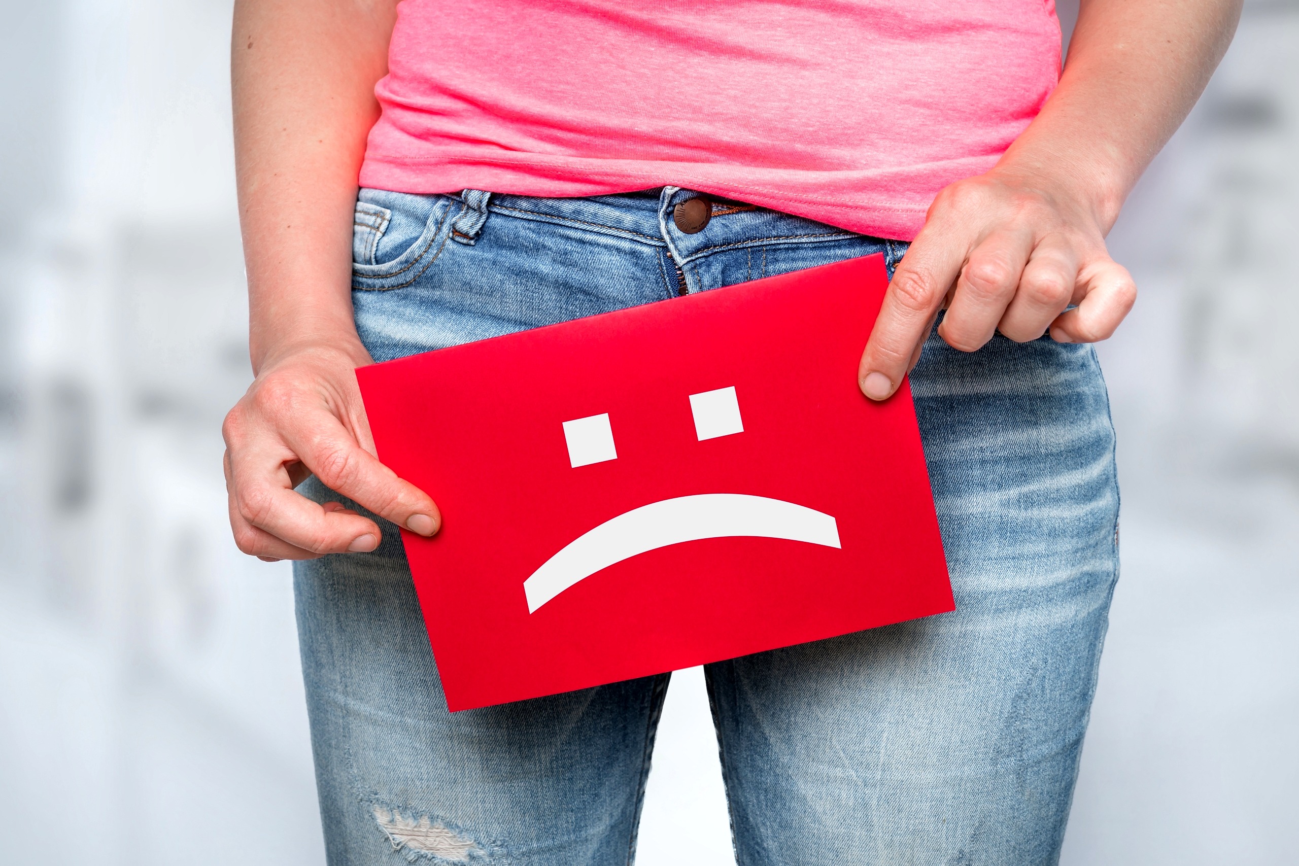 Woman with incontinence problem with sad smiley on paper
